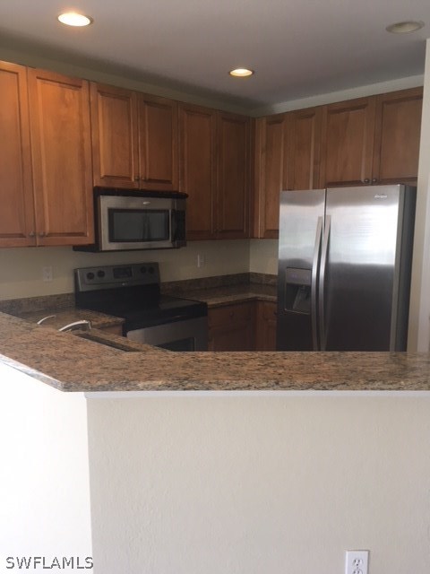 11711 Eros Road Lehigh Acres, FL 33971 - Photo 3 of 13 a kitchen with granite countertop a refrigerator a microwave a sink and cabinets