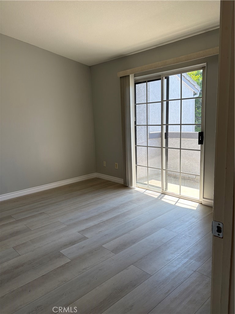 8248 Inglenook Place Rancho Cucamonga, CA 91730 - Photo 8 of 12 a view of an empty room with wooden floor and a window
