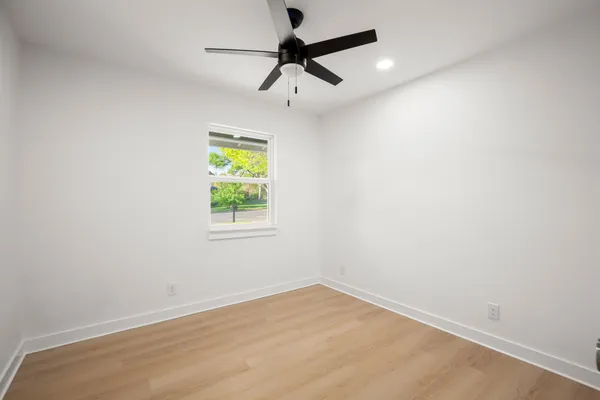 an empty room with window and ceiling fan