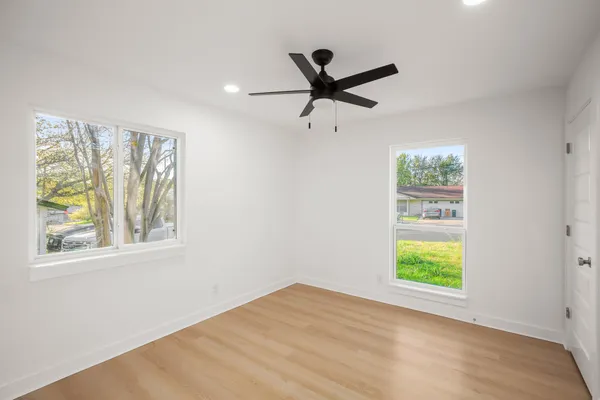 a view of an empty room with a window and wooden floor