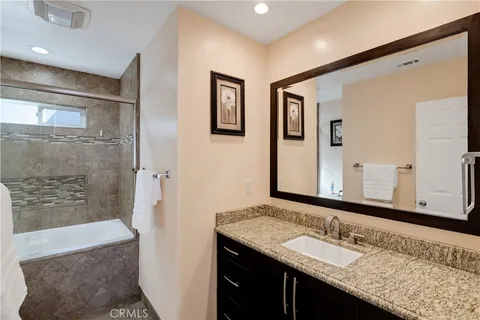 a bathroom with a granite countertop double vanity sink and mirror