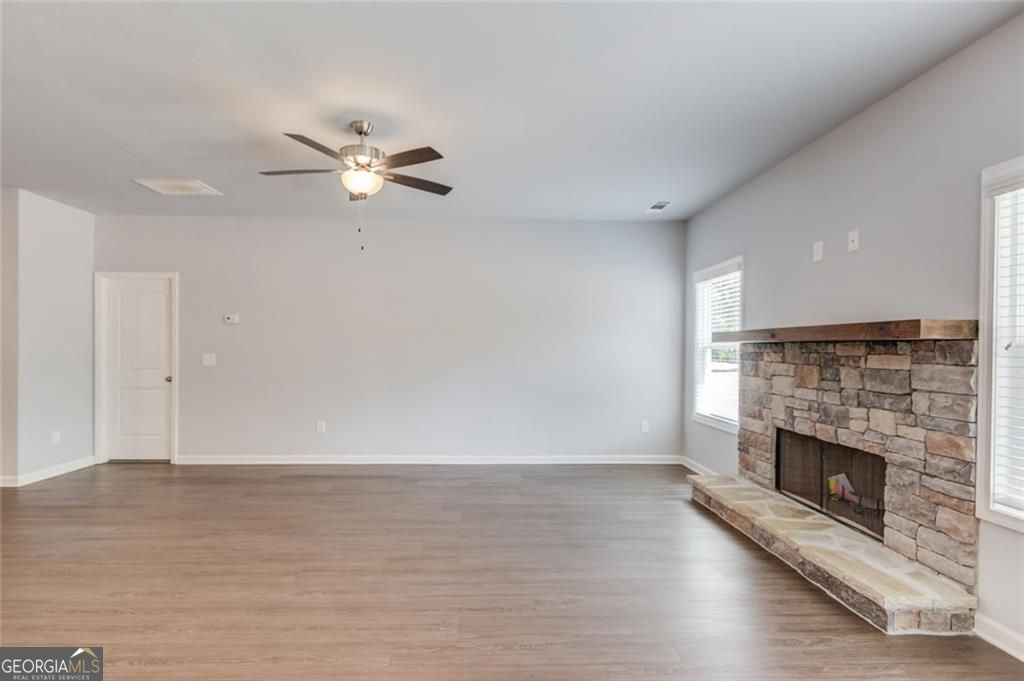 0 Harvest Church Road Clarkesville, GA 30523 - Photo 10 of 38 an empty room with wooden floor a fireplace a ceiling fan and a kitchen counter top