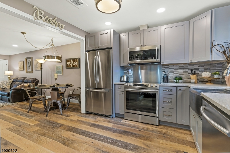 a kitchen with stainless steel appliances granite countertop a stove top oven a refrigerator and a sink