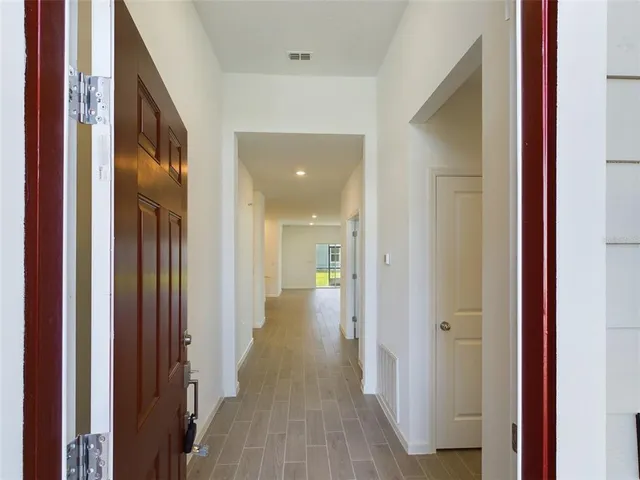 a view of a hallway with wooden floor and a bathroom