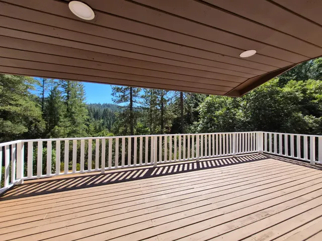 a view of balcony with wooden floor outdoor seating and yard in the back