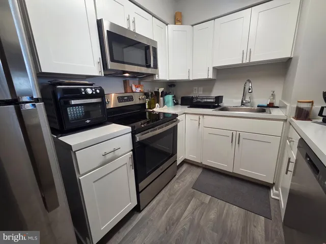 a kitchen with white cabinets stainless steel appliances and sink