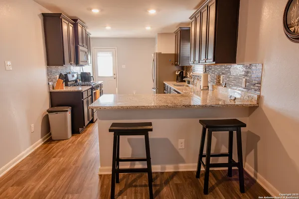 a kitchen with stainless steel appliances granite countertop a table chairs sink and cabinets