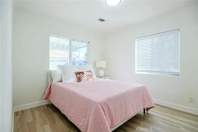 a large white kitchen with wooden floor and stainless steel appliances