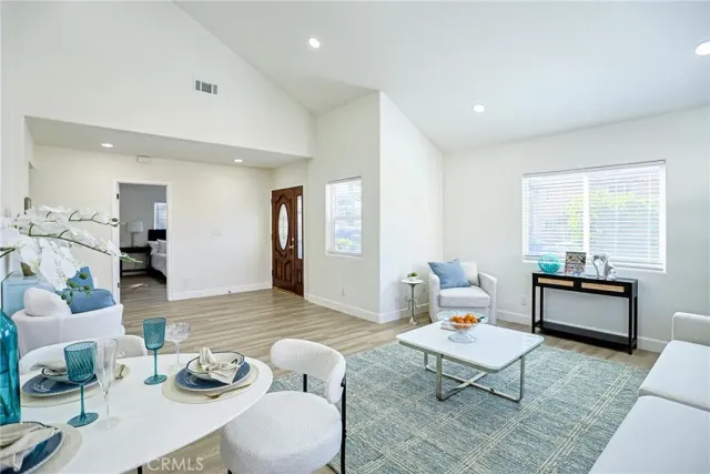 a living room with stainless steel appliances furniture a rug and a kitchen view