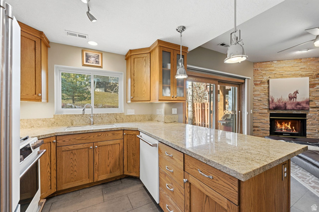 7930 Mustang Loop Road Park City, UT 84098 - Photo 23 of 23 Kitchen featuring decorative light fixtures, wood finish cabinetry, glass fronted cabinets, open floor plan, and light stone counters