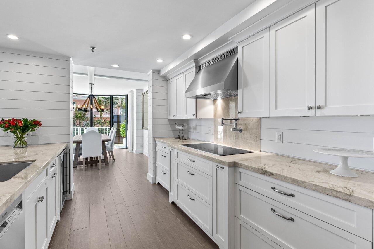 2917 South Ocean Boulevard, Unit 104 Highland Beach, FL 33487 - Photo 32 of 57 a kitchen with granite countertop white cabinets and white appliances