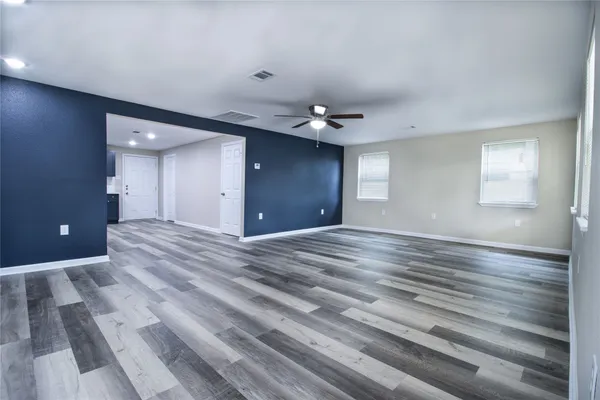 a view of an empty room with window and wooden floor