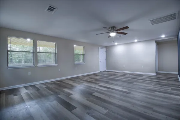 a view of an empty room with a window and wooden floor