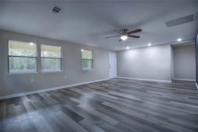 a view of an empty room with a window and wooden floor