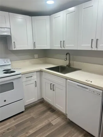 a kitchen with white cabinets appliances a sink and dishwasher