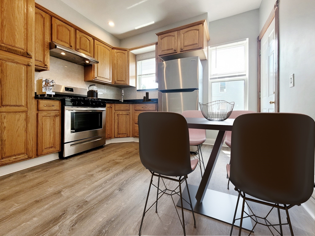 35 Dunlap Street, Unit 2 Boston, MA 02124 - Photo 4 of 12 a kitchen with stainless steel appliances granite countertop a stove a refrigerator a sink a dining table and chairs with wooden floor