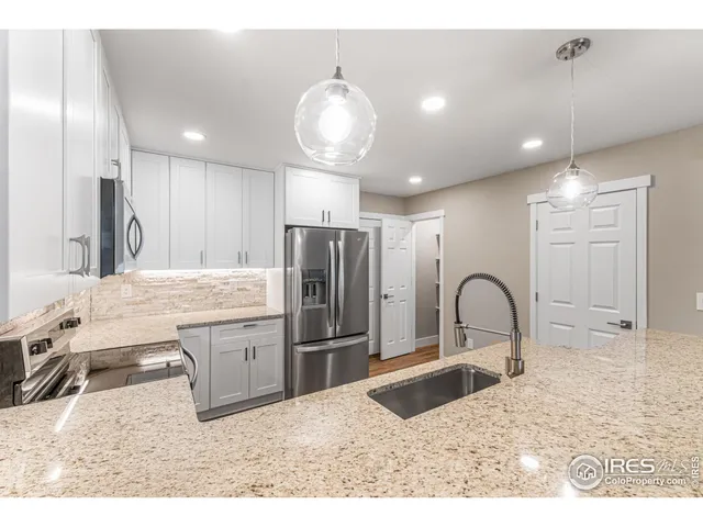 a kitchen with granite countertop a stove a refrigerator and a sink