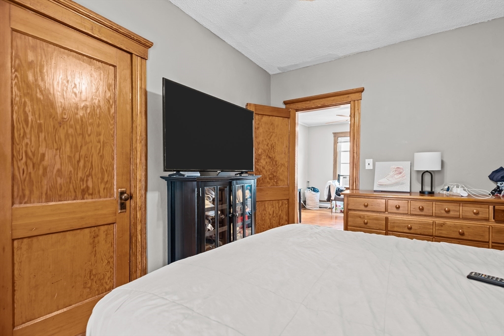 97 Warwick Street Woonsocket, RI 02895 - Photo 30 of 40 a bedroom with a bed and a flat tv screen on dresser