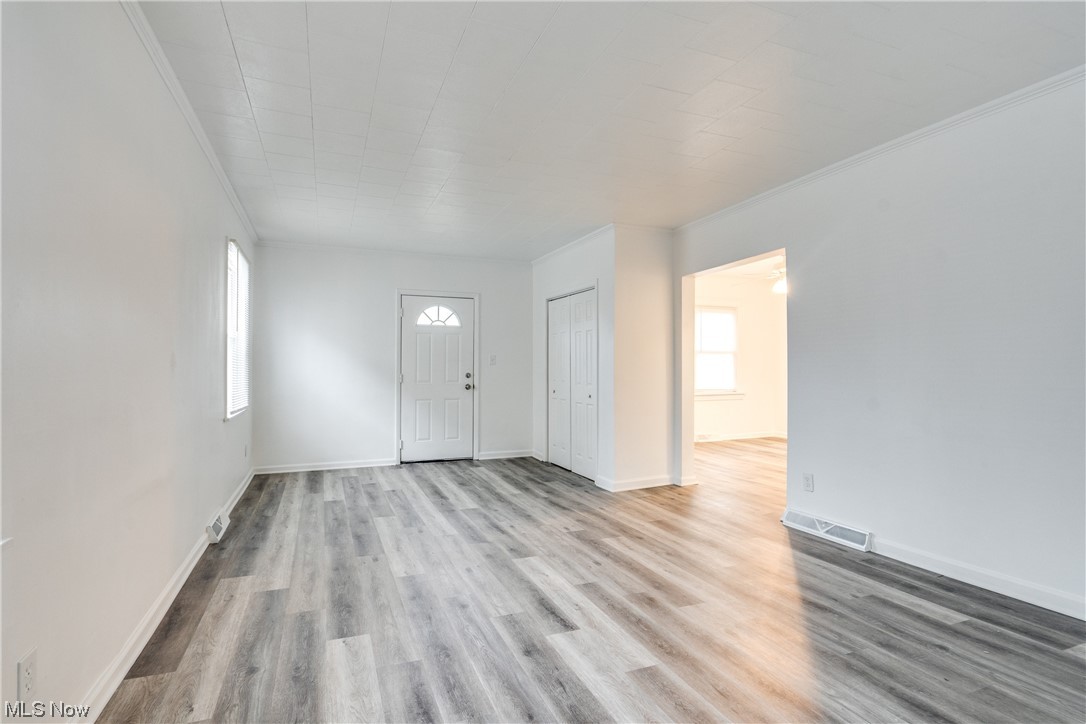 3219 Arbor Road Southwest Canton, OH 44710 - Photo 6 of 15 Spare room featuring ornamental molding, a healthy amount of sunlight, and light hardwood / wood-style floors