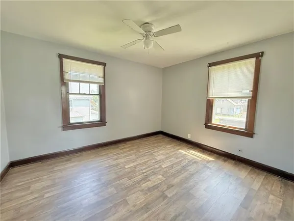 an empty room with wooden floor chandelier and windows
