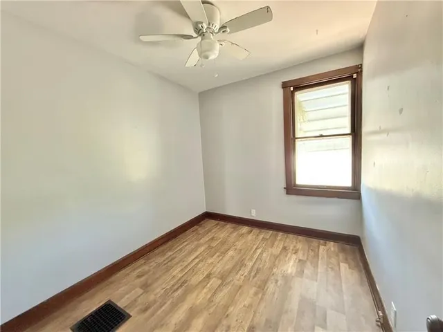 an empty room with a window and ceiling fan
