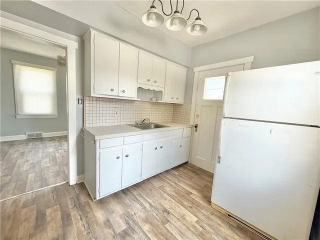 a kitchen with a refrigerator a sink and dishwasher with white cabinets