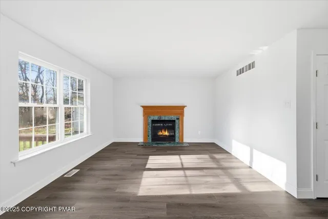 a view of an empty room with a window and fire place