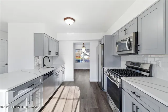 a kitchen with stainless steel appliances a sink cabinets and wooden floor
