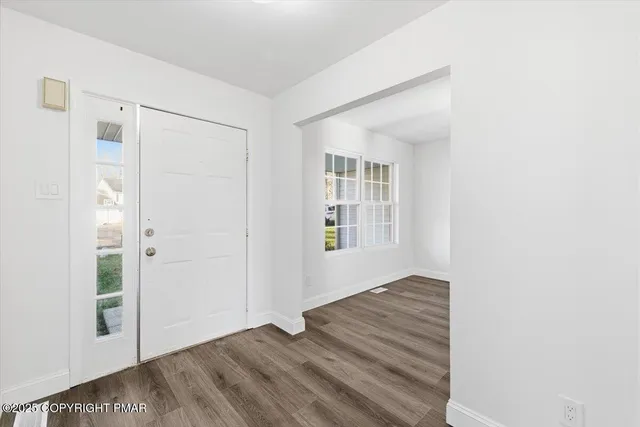 an empty room with wooden floor closet and windows