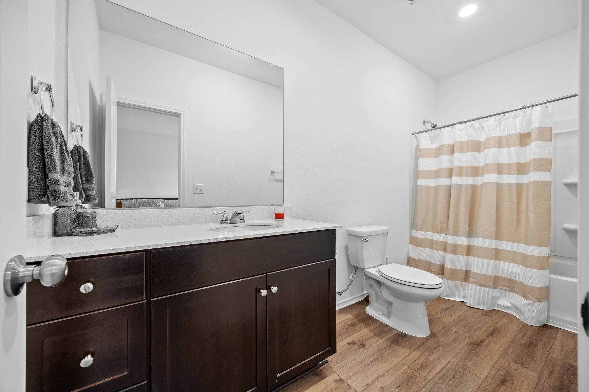 14121 Berning Road Manor, TX 78653 - Photo 11 of 27 A well-appointed bathroom features a single vanity, wood-look flooring, and a convenient shower-tub combination.