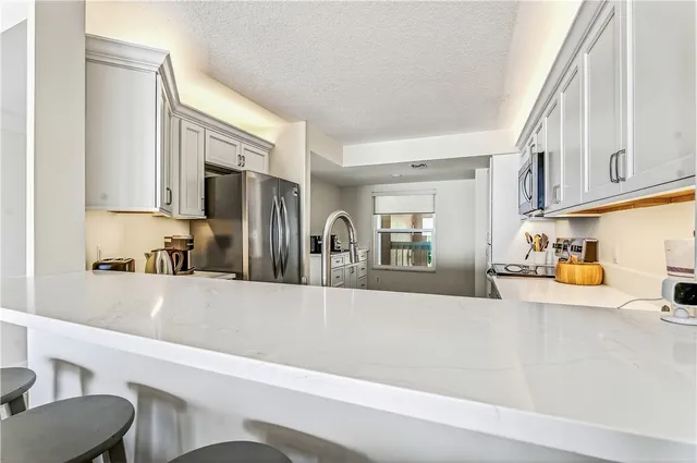 a living room with furniture a chandelier and a view of kitchen