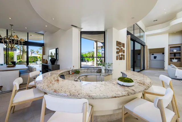 a view of a dining room with furniture a chandelier and large windows