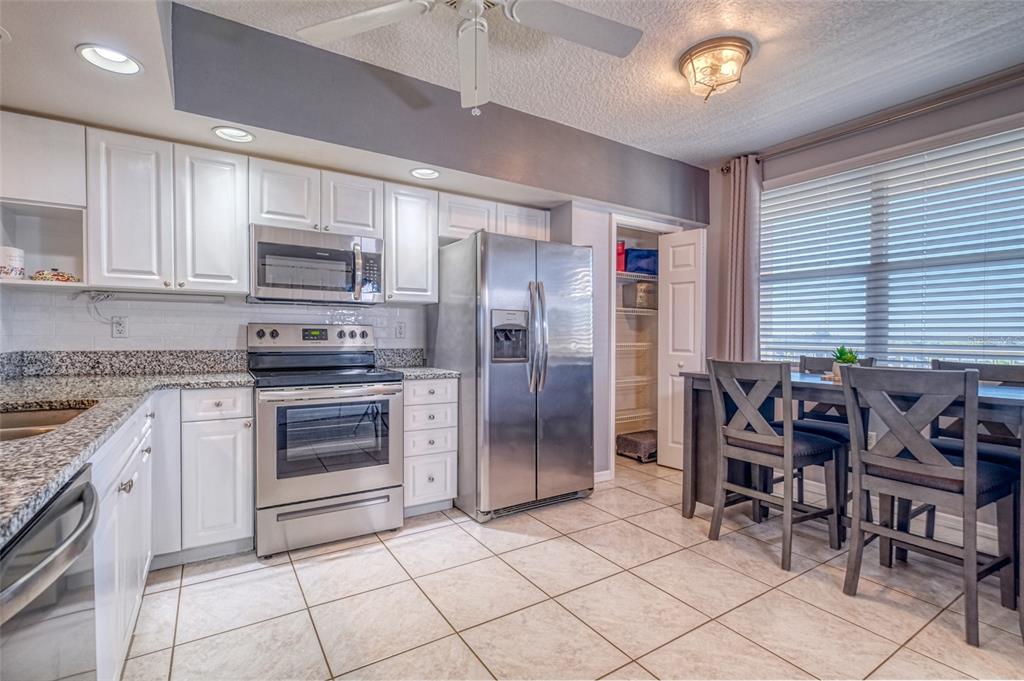 960 Starkey Road, Unit 1502 Largo, FL 33771 - Photo 8 of 36 a kitchen with stainless steel appliances granite countertop a stove top oven a refrigerator a sink and a dining table