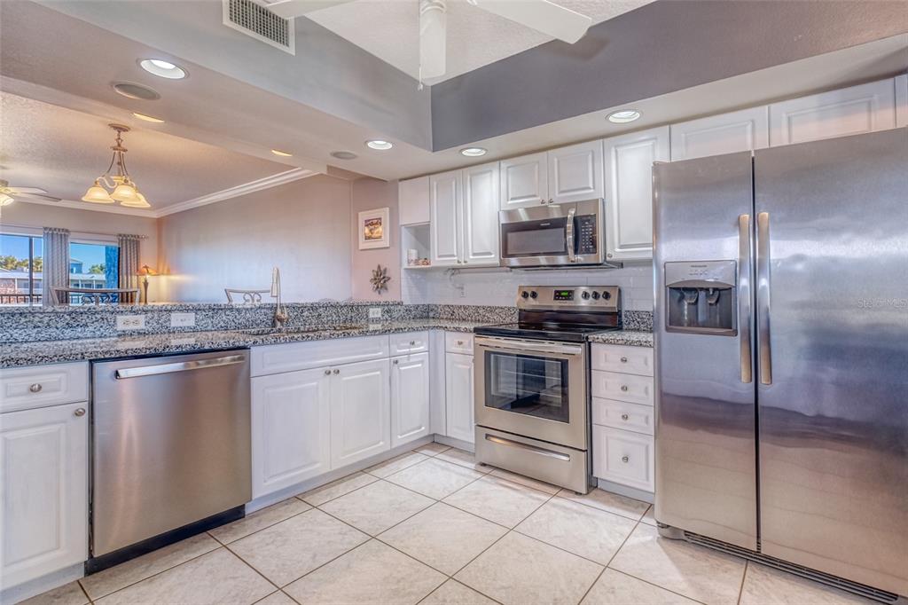 960 Starkey Road, Unit 1502 Largo, FL 33771 - Photo 9 of 36 a kitchen with stainless steel appliances granite countertop a stove a sink and a refrigerator