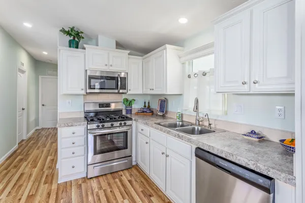 a kitchen with granite countertop a sink stainless steel appliances and cabinets