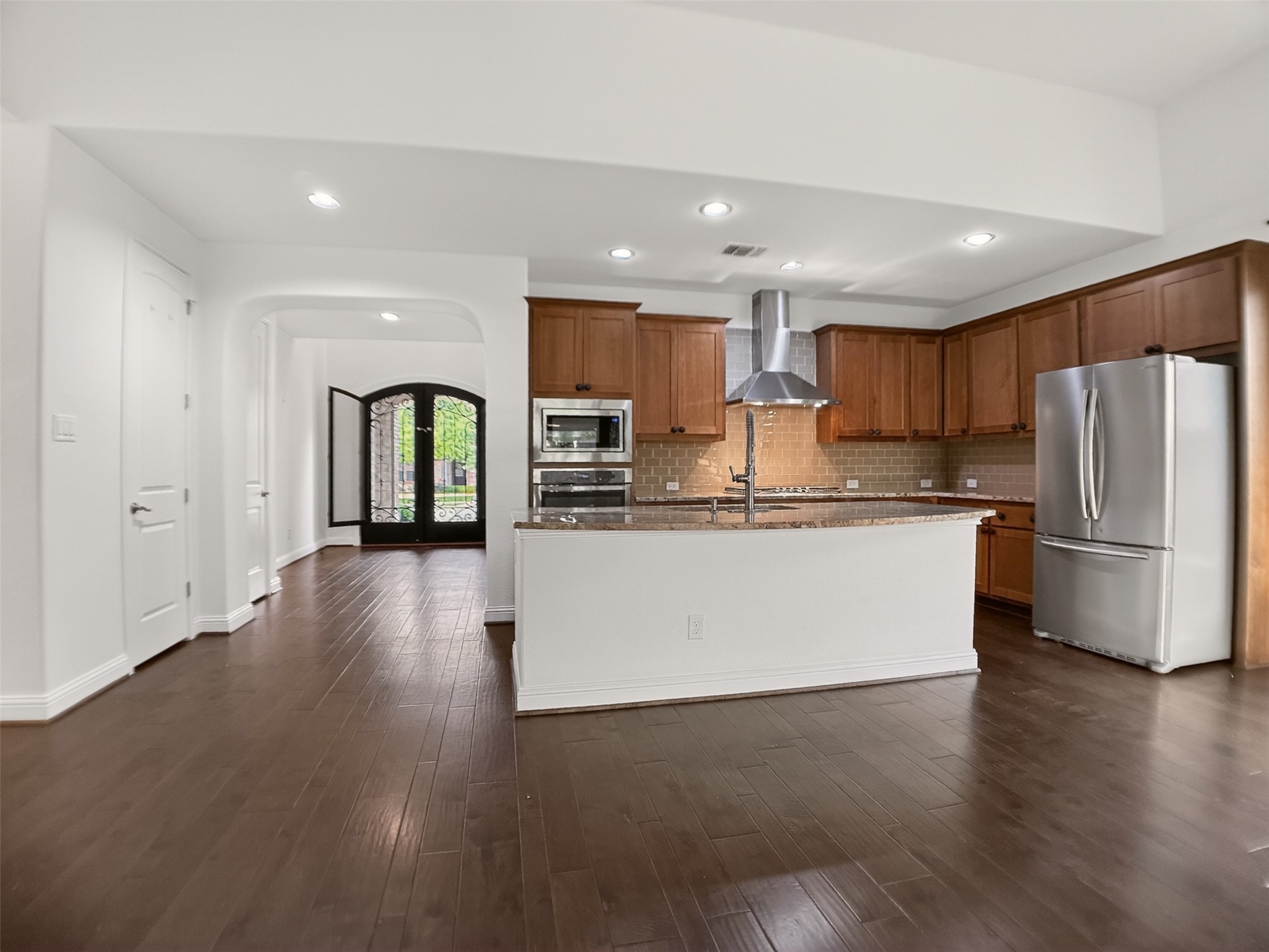 1505 Long Shadow Lane Georgetown, TX 78628 - Photo 5 of 28 Open-concept kitchen featuring wood-finish flooring, recessed lighting, and a kitchen island with a built-in sink