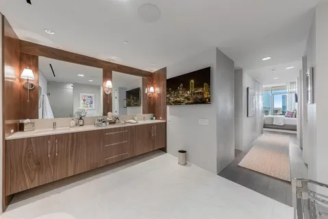 a large white room with a large mirror and view of living room
