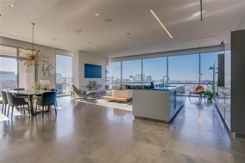 a living room with couches and kitchen view with wooden floor