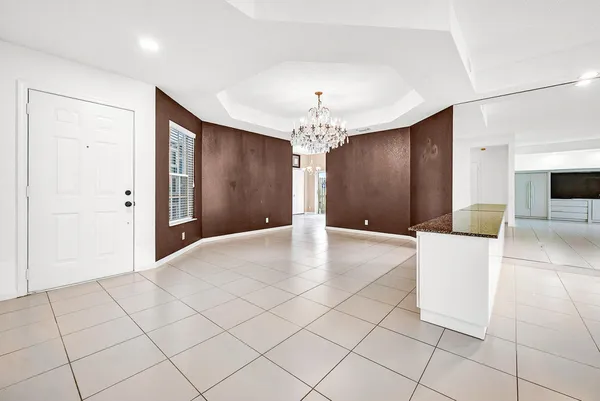 a view of a livingroom with a chandelier fan and kitchen space