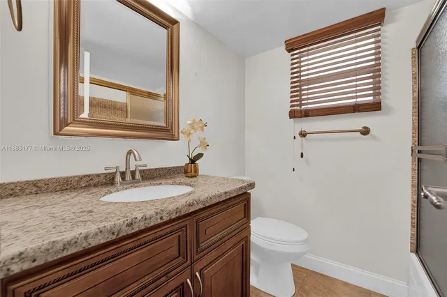 a bathroom with a granite countertop sink toilet and mirror