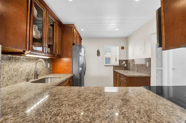a kitchen with granite countertop a sink and a refrigerator