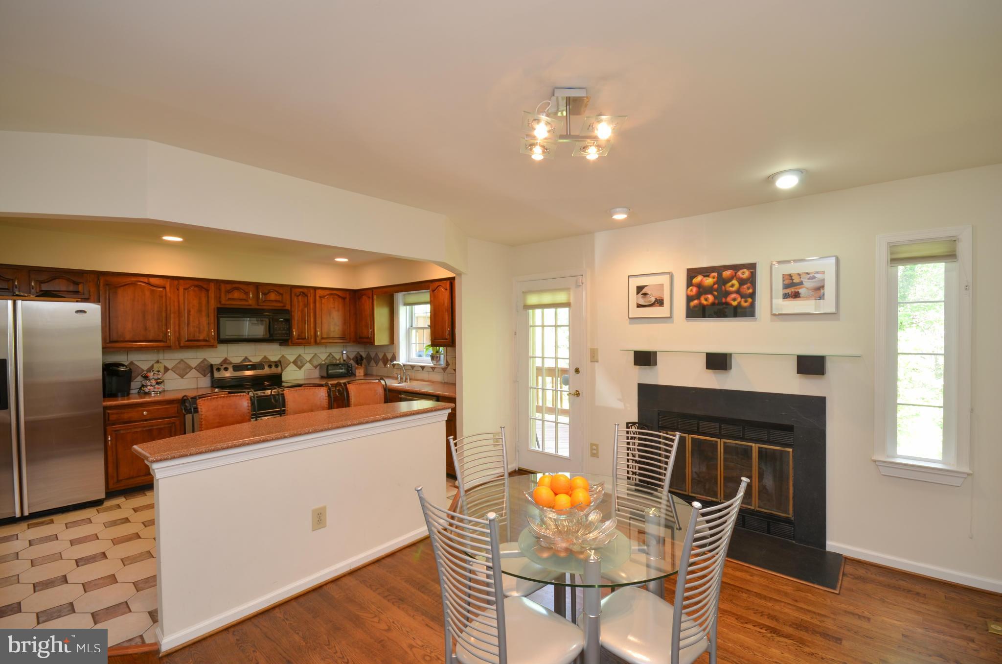 10771 Brewer House Road Rockville, MD 20852 - Photo 6 of 30 a kitchen with stainless steel appliances kitchen island granite countertop a refrigerator a stove a sink a dining table and chairs with wooden floor