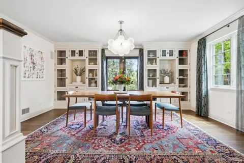 a dining room with wooden floor a chandelier a wooden table and chairs
