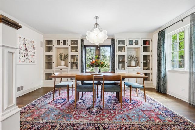 a dining room with wooden floor a chandelier a wooden table and chairs