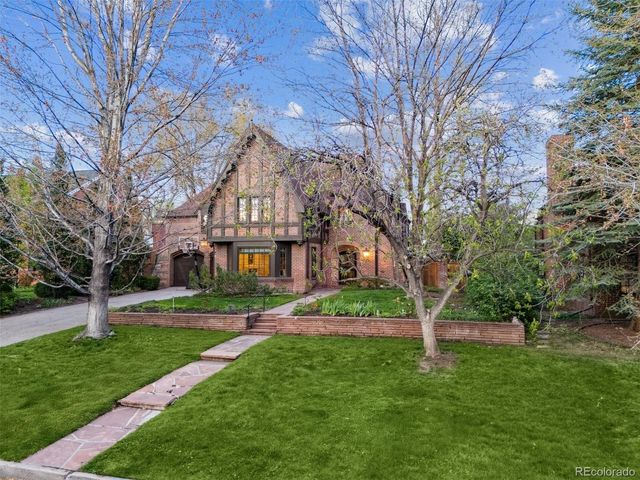 a view of house in front of a big yard with large trees