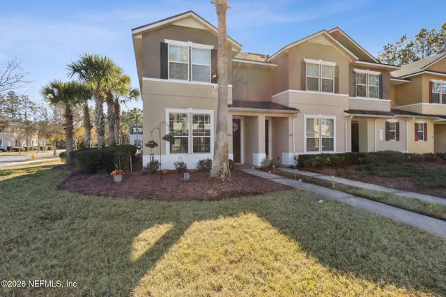 a view of a white house next to a yard with palm trees