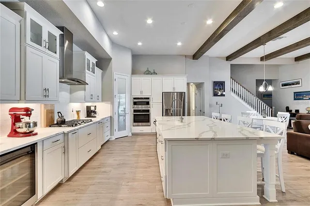 a large white kitchen with stainless steel appliances kitchen island a stove and a sink