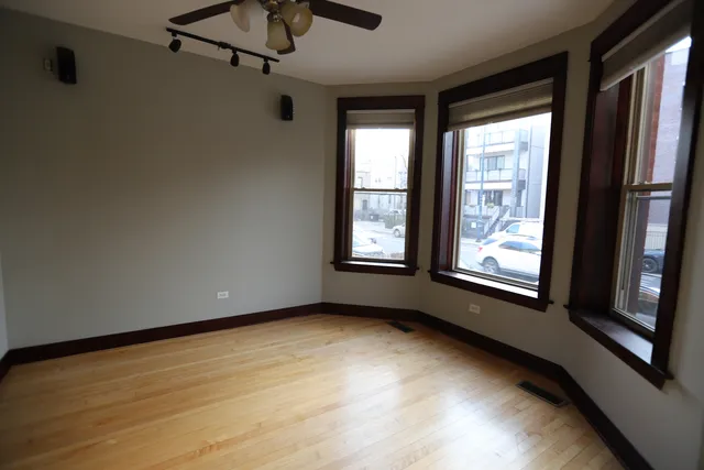 a view of an empty room with a window and wooden floor