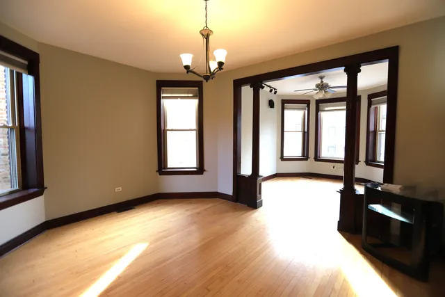 a view of an empty room with a window and wooden floor