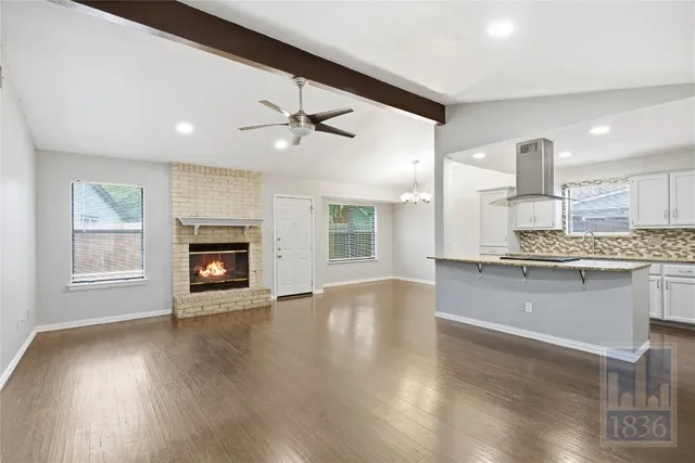 a view of an empty room with a kitchen and a fireplace